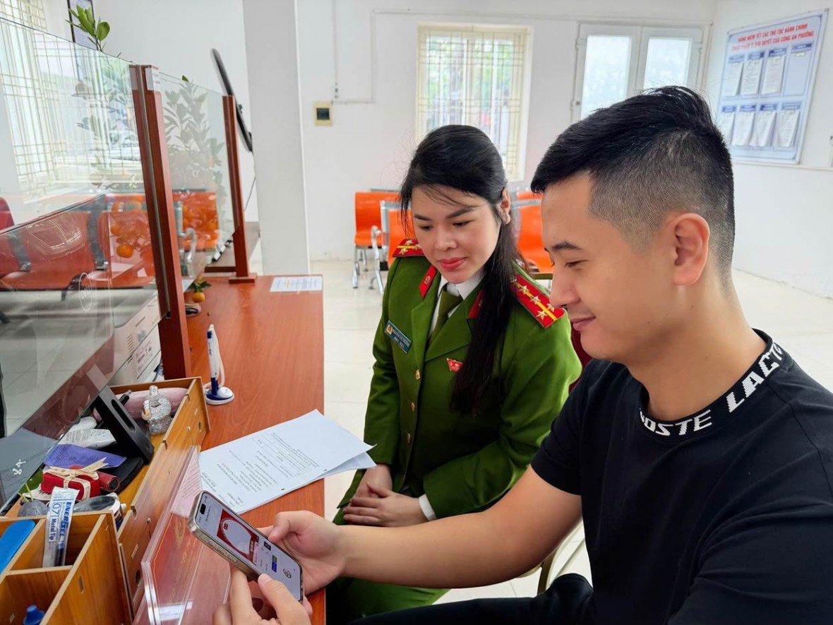 Tại trụ sở Công an phường Tây Hồ, CBCS Công an phường hướng dẫn người dân cài đặt hình nền chào mừng Đại hội XIV của Đảng.