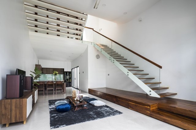 Giải ph&aacute;p thiết kế lệch tầng n&agrave;y ngay từ tầng 1 đ&atilde; tạo ra ph&acirc;n chia ước lượng giữa khu vực ph&ograve;ng kh&aacute;ch với ph&ograve;ng ăn, bếp qua chiều cao trần nh&agrave; đơn giản m&agrave; vẫn c&oacute; sự gắn kết.&nbsp;Cầu thang sử dụng thang bản th&eacute;p tạo cảm gi&aacute;c nhẹ nh&agrave;ng, th&ocirc;ng gi&oacute; xuy&ecirc;n ph&ograve;ng v&agrave; kh&ocirc;ng cản tầm nh&igrave;n c&aacute;c kh&ocirc;ng gian trong nh&agrave;.