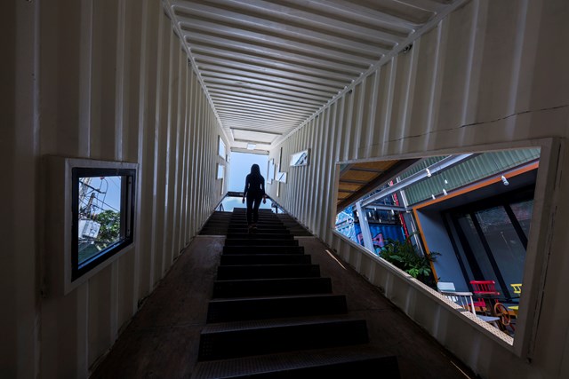 Một container d&agrave;i đặt ở một g&oacute;c kh&ocirc;ng chắc chắn v&agrave; bị xuy&ecirc;n thủng bởi những đường cắt bất thường tạo n&ecirc;n một cầu thang kết th&uacute;c với khung cảnh bầu trời. Nhiều đường cắt của n&oacute; kết nối bất ngờ c&aacute;c kh&ocirc;ng gian liền kề, kết nối tạo th&agrave;nh khu phức hợp. &nbsp;