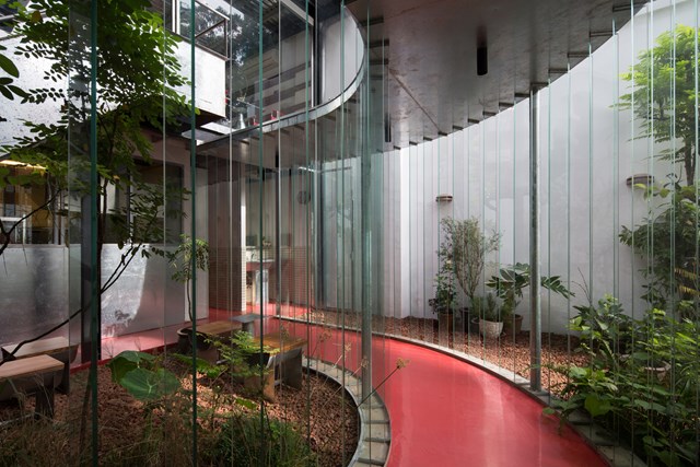 Tất cả được kết nối với nhau bằng một lối đi kh&eacute;p k&iacute;n.&nbsp;Cửa k&iacute;nh dọc lối đi ph&acirc;n định tinh tế giữa b&ecirc;n trong v&agrave; b&ecirc;n ngo&agrave;i. Ch&uacute;ng hấp thụ, phản xạ cả &aacute;nh s&aacute;ng v&agrave; m&ocirc;i trường xung quanh. S&agrave;n epoxy m&agrave;u đỏ thu h&uacute;t sự ch&uacute; &yacute; của mọi người từ trước ra sau. &nbsp;