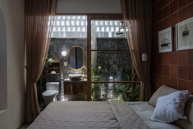 Thiết kế ph&ograve;ng ngủ với t&ocirc;ng m&agrave;u n&acirc;u đơn giản nhưng ấm c&uacute;ng với một cửa k&iacute;nh lớn hướng ra khu vườn xanh.