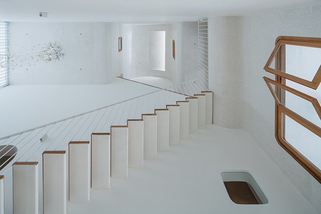 Cầu thang phối m&agrave;u trắng v&agrave; gỗ nằm ở trung t&acirc;m căn nh&agrave; l&agrave; kh&ocirc;ng gian giao th&ocirc;ng ch&iacute;nh. Đ&acirc;y l&agrave; điểm nhấn của c&ocirc;ng tr&igrave;nh tạo ra kh&ocirc;ng gian tho&aacute;ng đ&atilde;ng, hiện đại v&agrave; kết nối giữa c&aacute;c tầng. &nbsp;