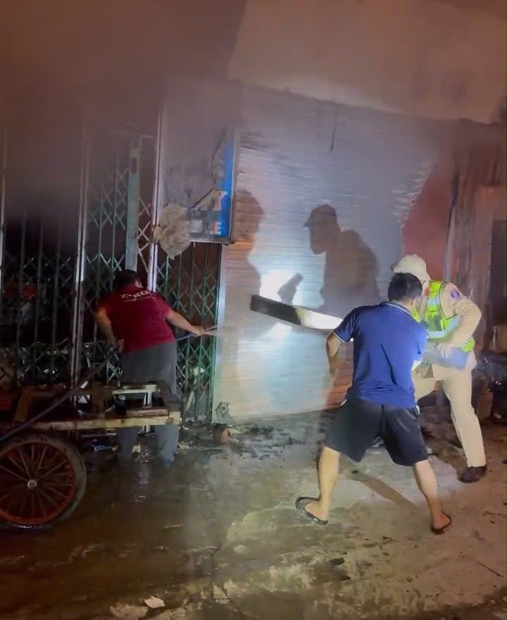 Cùng người dân, lực lượng CSGT phá cửa, hỗ trợ đưa 11 người ra ngoài an toàn - Ảnh Công an Nghệ An.