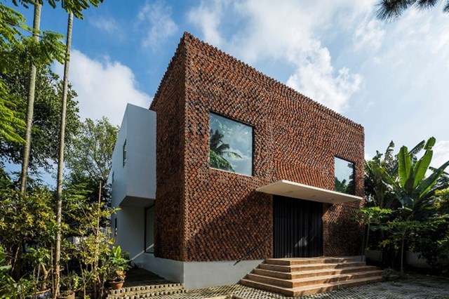 Thoạt nh&igrave;n ng&ocirc;i nh&agrave; tr&ocirc;ng giống như chiếc tổ ong với những chiếc lỗ trải đều từ tr&ecirc;n xuống dưới, nhưng &iacute;t ai ngờ việc sắp xếp những vi&ecirc;n gạch nghi&ecirc;ng, c&ugrave;ng m&agrave;u sắc đỏ của gạch tạo n&ecirc;n vẻ ngo&agrave;i độc đ&aacute;o cho ng&ocirc;i nh&agrave;.