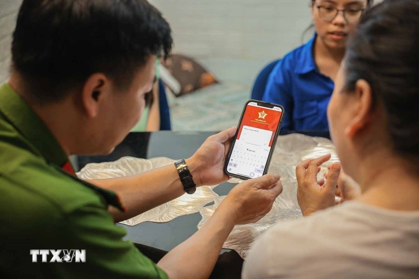 Tổ chuyển đổi số cộng đồng hướng dẫn người dân sử dụng ứng dụng VNeID. Ảnh: TTXVN