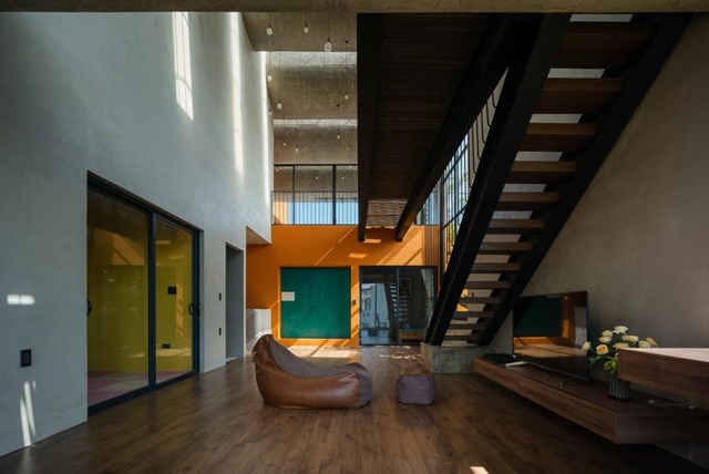 Một kh&ocirc;ng gian ph&ograve;ng kh&aacute;ch kh&aacute;c được thiết kế th&ocirc;ng tầng với nội thất gam m&agrave;u n&acirc;u đơn giản m&agrave; thanh lịch.