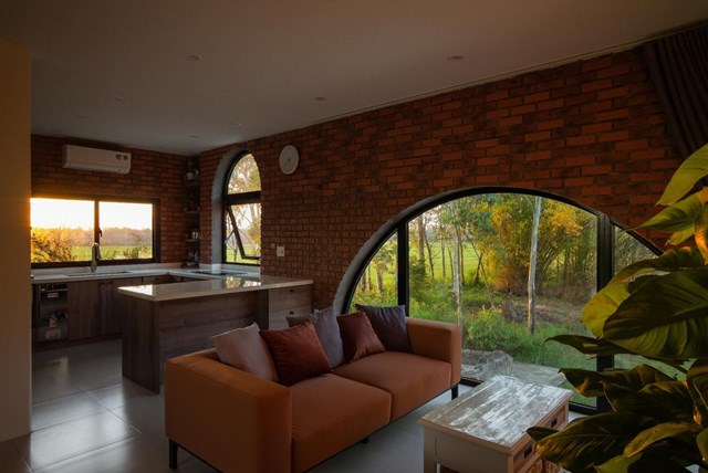 Kh&ocirc;ng gian sinh hoạt chung của gia đ&igrave;nh được đặt tại tầng 2. Ph&ograve;ng kh&aacute;ch thiết kế liền kề với khu bếp. Nội thất gam m&agrave;u n&acirc;u cam kết hợp h&agrave;i h&ograve;a với m&agrave;u gạch tường.&nbsp;