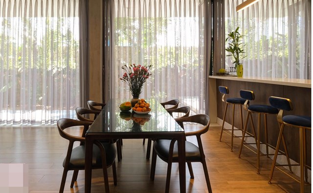 B&agrave;n ăn v&agrave; khu bếp liền kề với ph&ograve;ng kh&aacute;ch, ph&aacute; bỏ giới hạn, k&eacute;o gần c&aacute;c th&agrave;nh vi&ecirc;n lại với nhau qua c&aacute;c hoạt động thường ng&agrave;y. Kh&ocirc;ng gian trải rộng tr&ecirc;n c&ugrave;ng một mặt phẳng gia tăng đối lưu kh&ocirc;ng kh&iacute; v&agrave; th&ocirc;ng gi&oacute; tự nhi&ecirc;n cho ng&ocirc;i nh&agrave; trong m&ocirc;i trường nhiệt đới ẩm của Nha Trang.