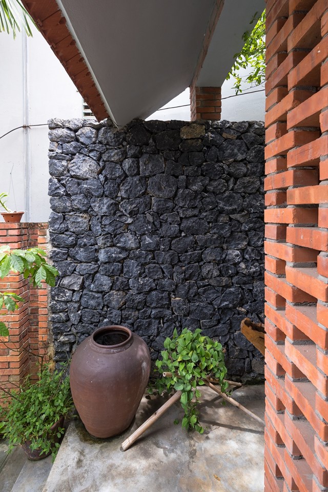 Chạy dọc hai b&ecirc;n cạnh nh&agrave; l&agrave; bức tường r&agrave;o được x&acirc;y bằng đ&aacute; đen sẫm. Đ&acirc;y l&agrave; những vi&ecirc;n đ&aacute; t&aacute;i chế, thu lượm được trong qu&aacute; tr&igrave;nh đ&agrave;o những trụ m&oacute;ng của c&ocirc;ng tr&igrave;nh v&agrave; san nền cho c&aacute;c khoảng s&acirc;n.&nbsp;